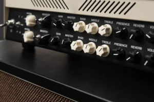A imagem mostra o painel de controle de um amplificador de guitarra, com vários botões pretos e brancos para ajustar configurações como Booster, Gain, Master, Bass, Middle, Treble, Presence e Reverb.